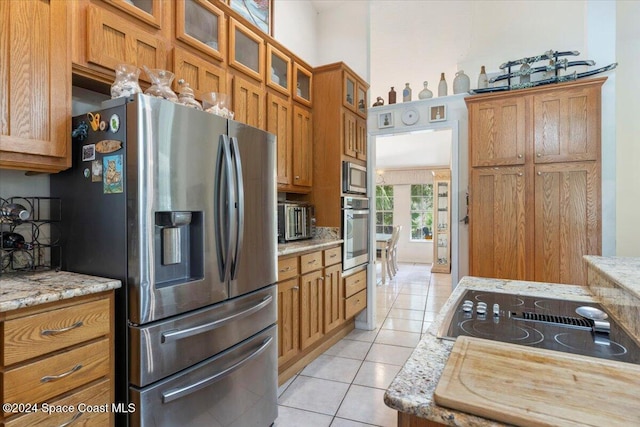 kitchen featuring light tile patterned floors, stainless steel appliances, and light stone counters