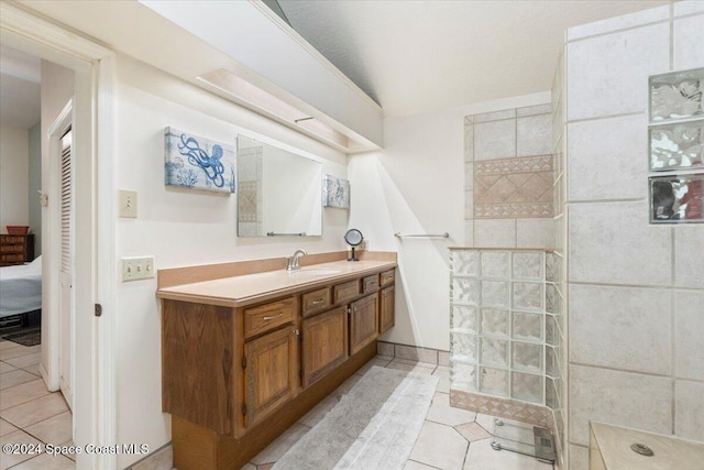 bathroom with tile patterned flooring, vanity, and tiled shower