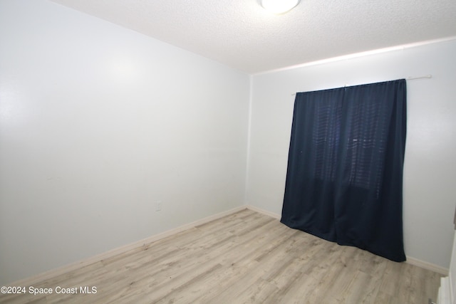 unfurnished room featuring a textured ceiling and light wood-type flooring