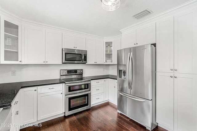 kitchen with dark stone counters, white cabinets, dark wood-type flooring, and appliances with stainless steel finishes