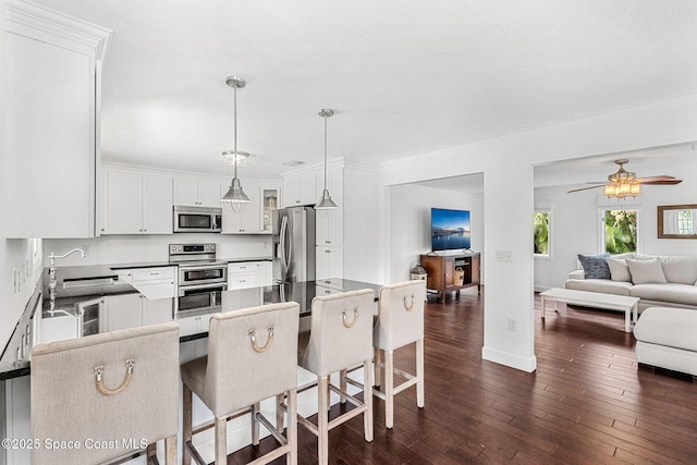 kitchen with decorative light fixtures, a kitchen breakfast bar, white cabinetry, and appliances with stainless steel finishes