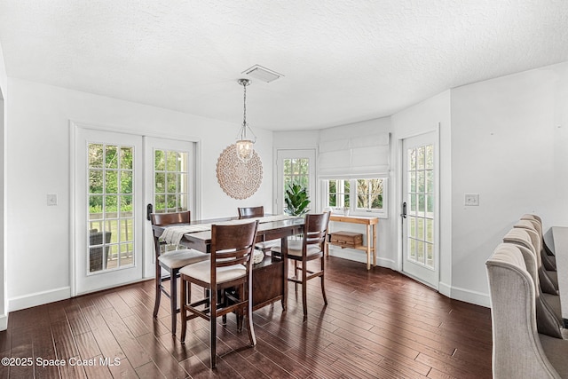 dining room with a textured ceiling and dark wood-type flooring