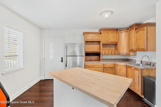 kitchen with stainless steel fridge, sink, a kitchen island, and dark hardwood / wood-style floors