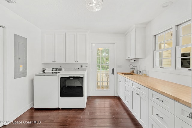 laundry room with washer and clothes dryer, cabinets, electric panel, sink, and dark hardwood / wood-style flooring