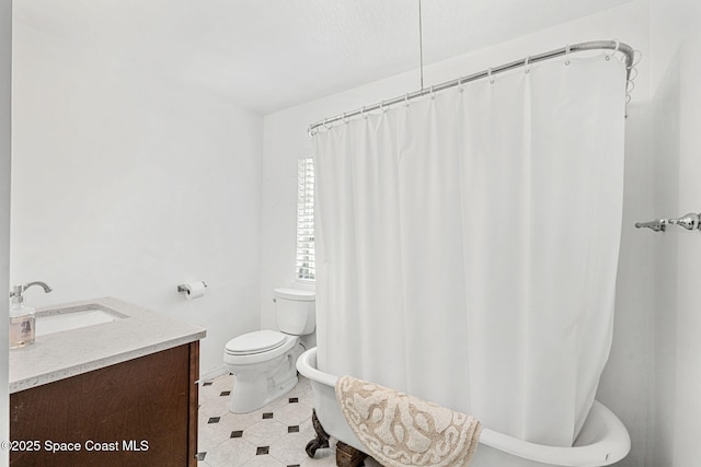 bathroom featuring vanity, a tub to relax in, and toilet