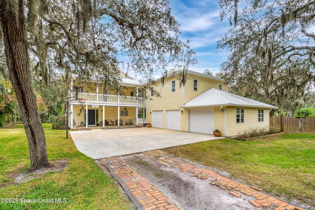 front of property with covered porch, a garage, a balcony, and a front lawn