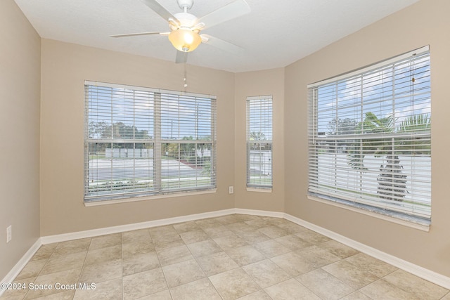 empty room featuring ceiling fan, light tile patterned floors, and a textured ceiling