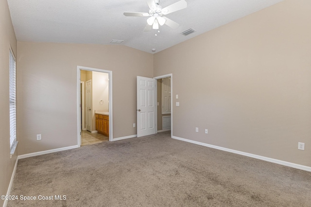 unfurnished bedroom featuring connected bathroom, light colored carpet, ceiling fan, and lofted ceiling