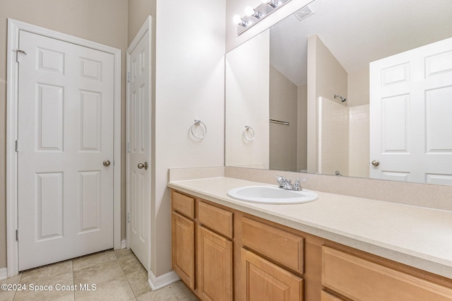 bathroom with tile patterned flooring, vanity, and walk in shower