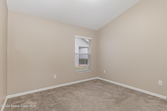 unfurnished room with lofted ceiling and light carpet