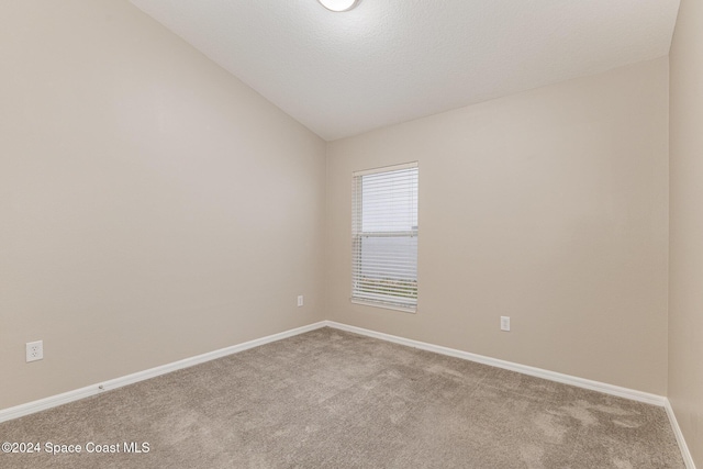 carpeted spare room with lofted ceiling