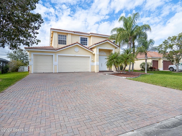 mediterranean / spanish house featuring a front yard and a garage