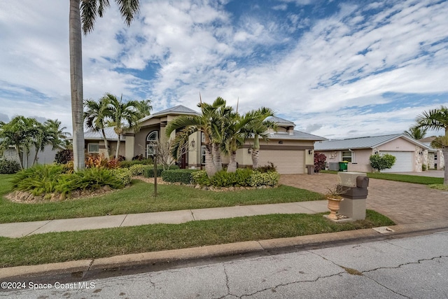 view of front facade with a front lawn, decorative driveway, a garage, and stucco siding