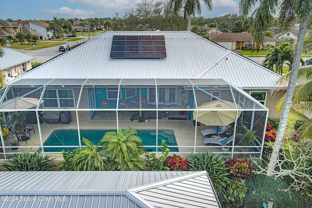 rear view of property with a patio, a lanai, and solar panels