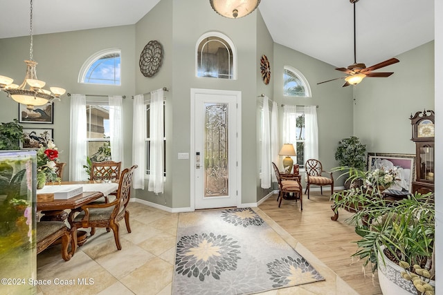 entryway with a healthy amount of sunlight, ceiling fan with notable chandelier, high vaulted ceiling, and light hardwood / wood-style flooring