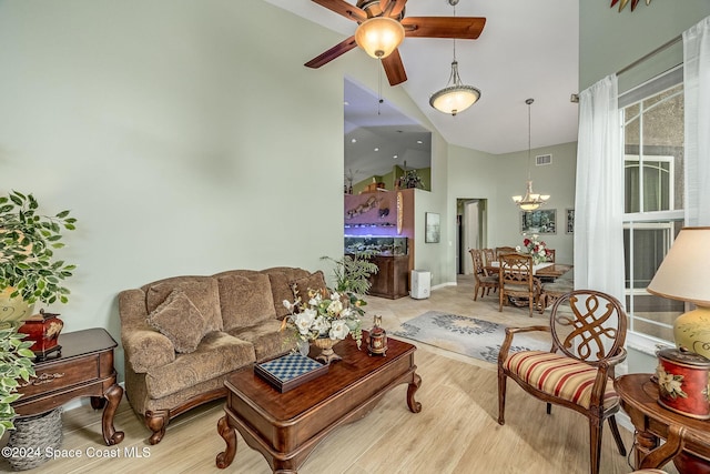 living room with high vaulted ceiling, ceiling fan with notable chandelier, and light hardwood / wood-style floors