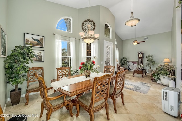 tiled dining room featuring ceiling fan with notable chandelier and high vaulted ceiling