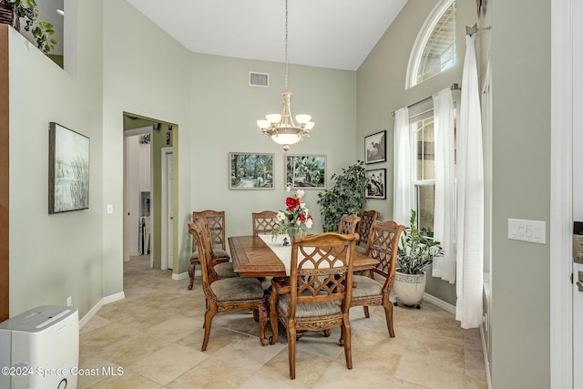 dining area with an inviting chandelier and a towering ceiling