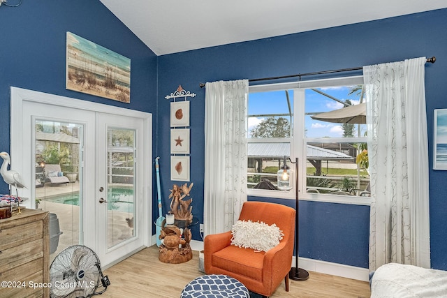 living area featuring french doors, vaulted ceiling, and light hardwood / wood-style flooring