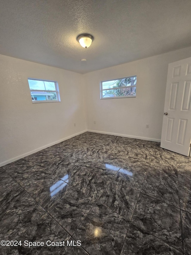 empty room with plenty of natural light and a textured ceiling