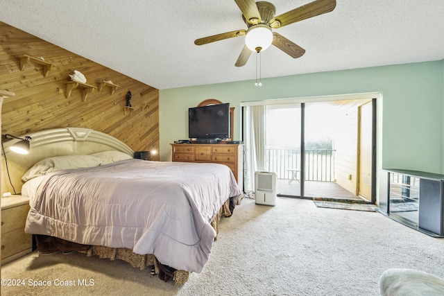 bedroom with wooden walls, ceiling fan, a textured ceiling, and access to outside