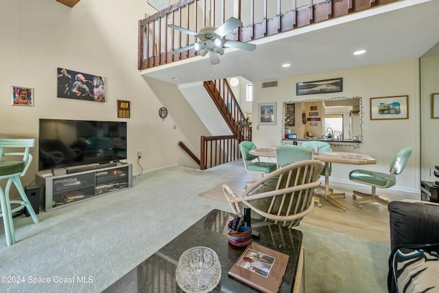 living room featuring ceiling fan, a towering ceiling, and wood-type flooring