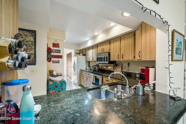 kitchen featuring kitchen peninsula, dark stone counters, stainless steel appliances, sink, and light tile patterned floors