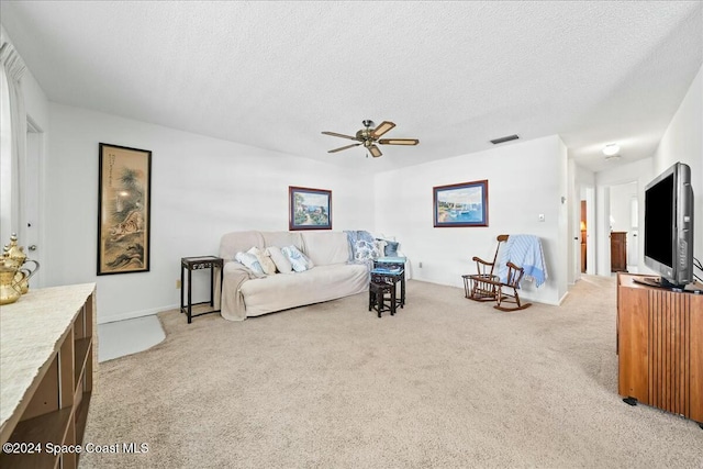 living room featuring a textured ceiling, light colored carpet, and ceiling fan