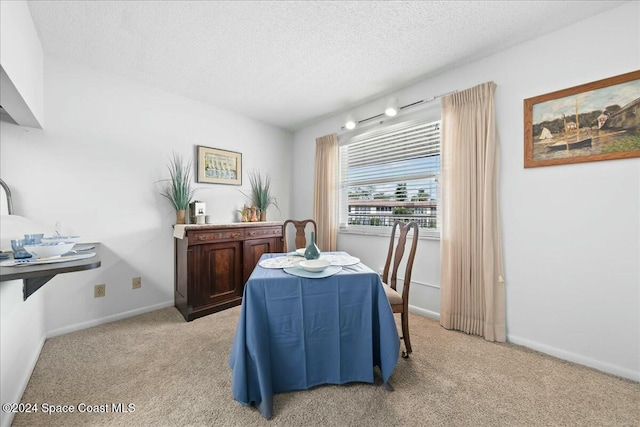 dining space with light carpet and a textured ceiling