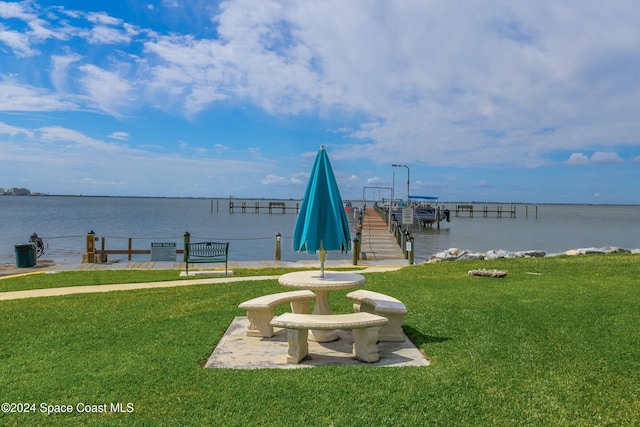 view of dock with a water view and a lawn