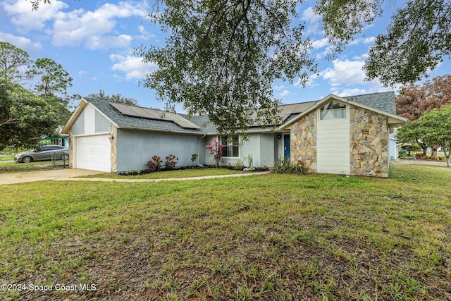 ranch-style home with solar panels, a garage, and a front yard