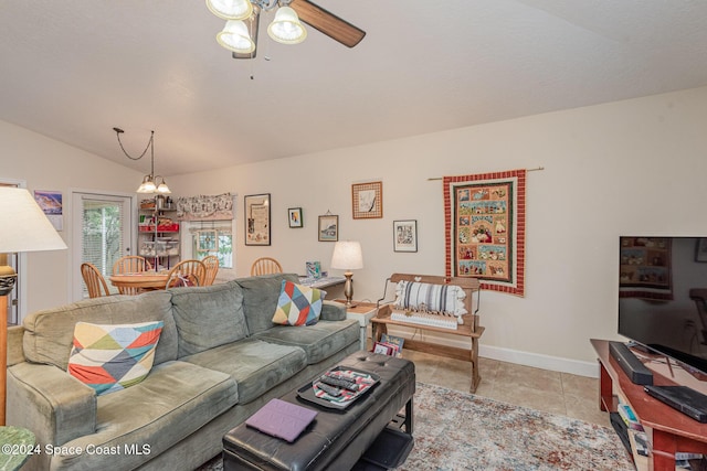 tiled living room with ceiling fan with notable chandelier and lofted ceiling