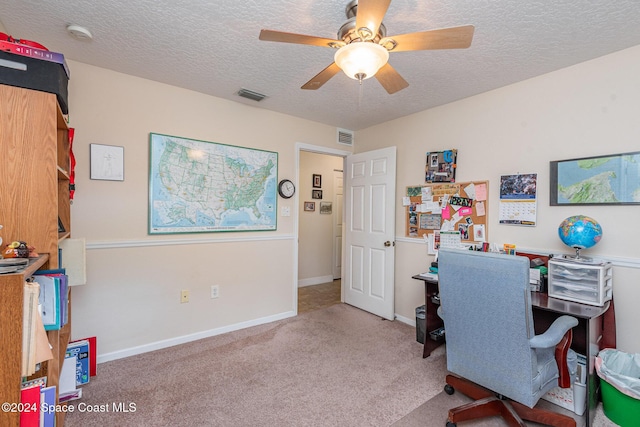 carpeted office space featuring ceiling fan and a textured ceiling