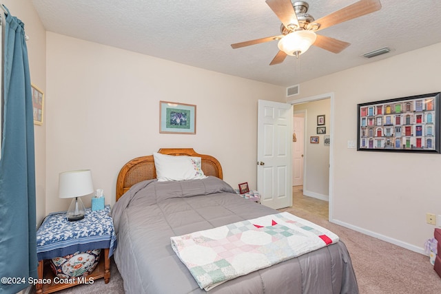 carpeted bedroom featuring ceiling fan and a textured ceiling