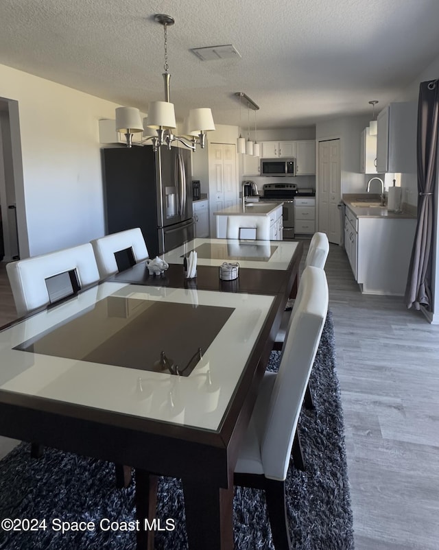 kitchen with appliances with stainless steel finishes, a textured ceiling, decorative light fixtures, and dark hardwood / wood-style flooring