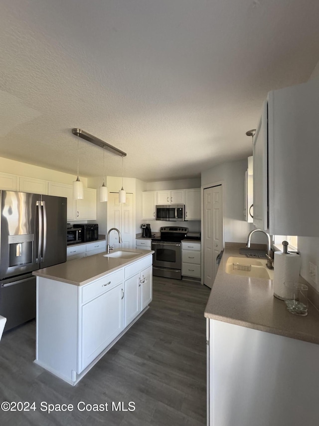 kitchen featuring white cabinetry, sink, hanging light fixtures, and appliances with stainless steel finishes