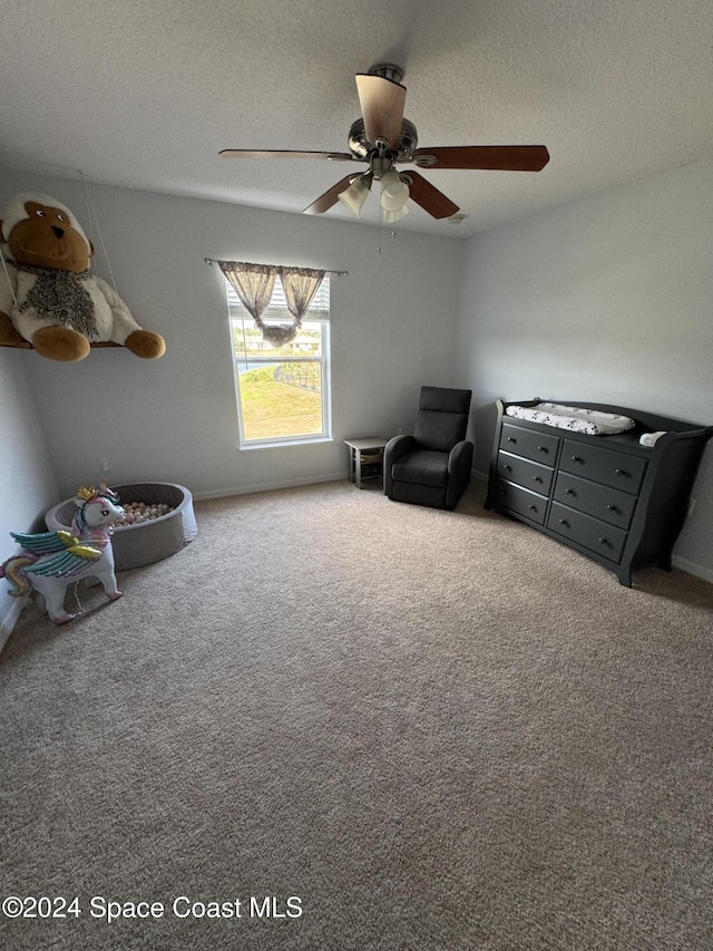 interior space featuring ceiling fan, carpet floors, and a textured ceiling