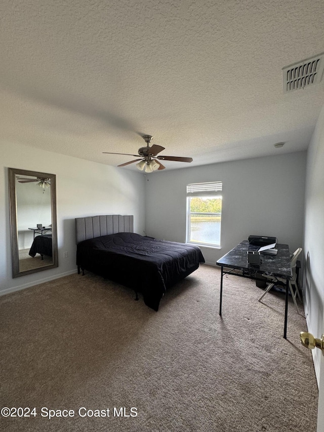 carpeted bedroom featuring ceiling fan and a textured ceiling