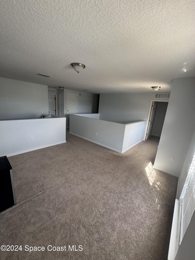 carpeted empty room with a textured ceiling