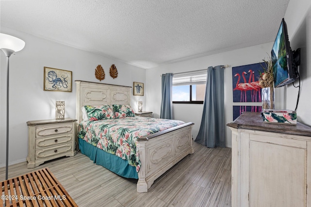 bedroom with a textured ceiling and light hardwood / wood-style flooring