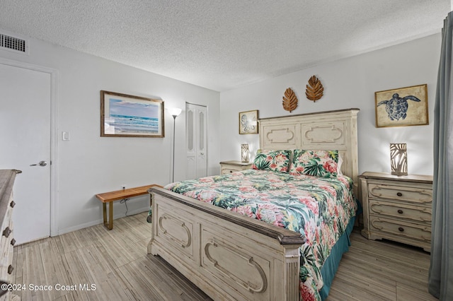 bedroom featuring a closet, a textured ceiling, and light hardwood / wood-style flooring