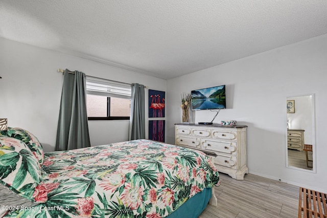 bedroom with light hardwood / wood-style floors and a textured ceiling