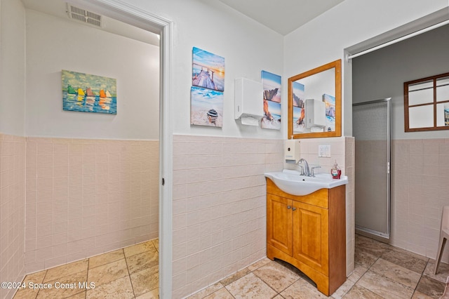 bathroom featuring vanity and tile walls