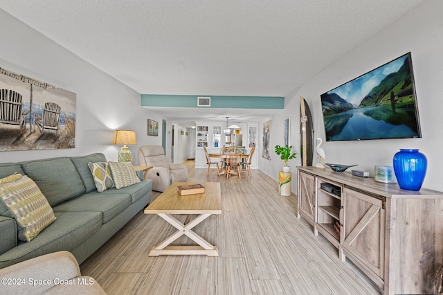 living room featuring light wood-type flooring and a textured ceiling