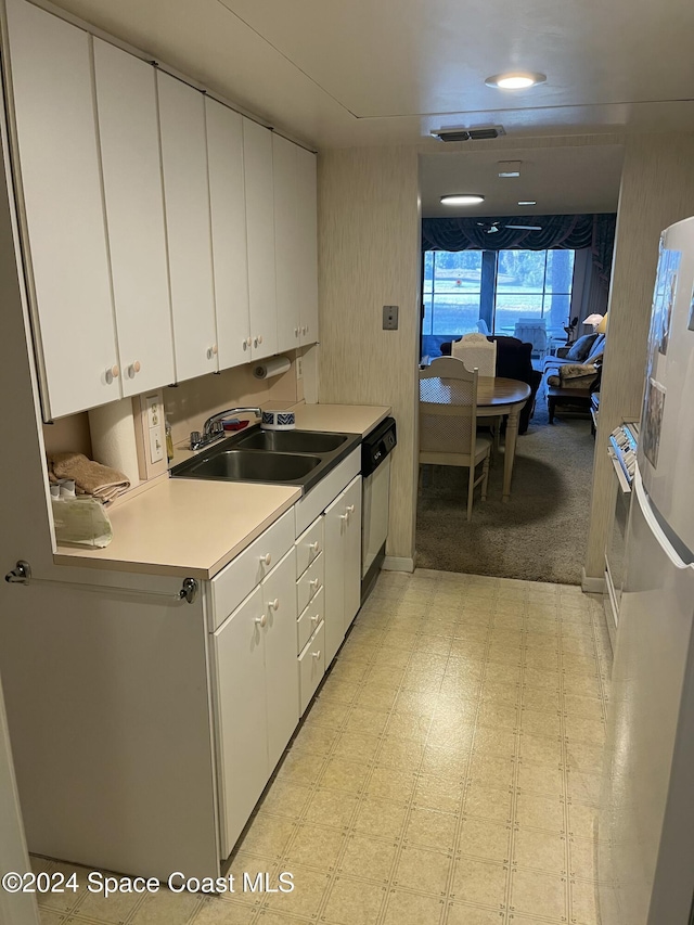 kitchen featuring dishwasher, white refrigerator, white cabinetry, and sink