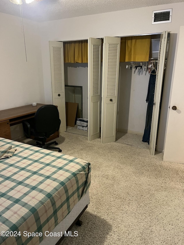 bedroom with carpet floors, a textured ceiling, and two closets