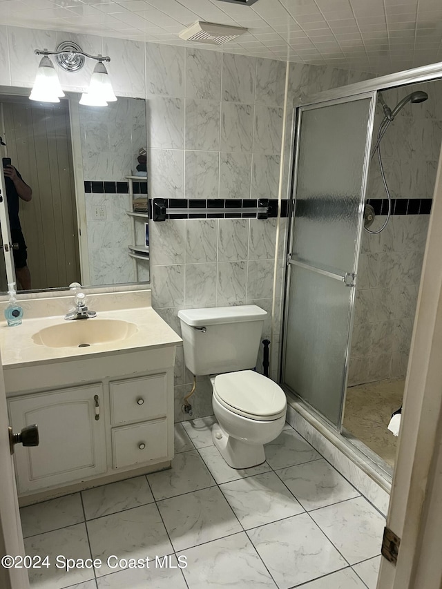 bathroom featuring an enclosed shower, vanity, toilet, and tile walls