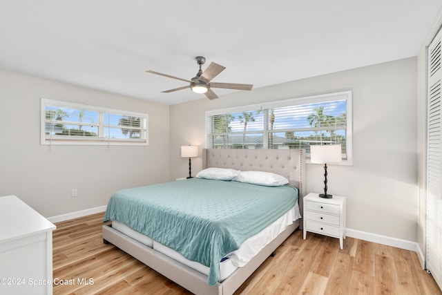 bedroom featuring ceiling fan, light hardwood / wood-style floors, and multiple windows