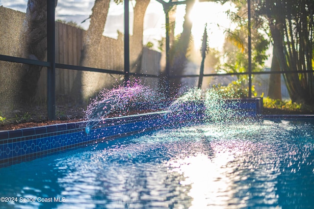 view of swimming pool featuring glass enclosure