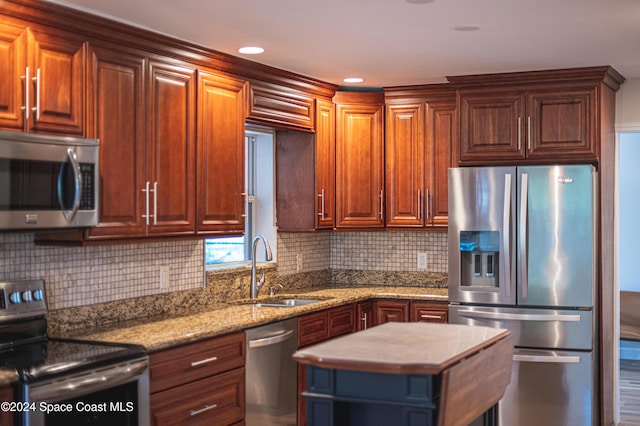 kitchen featuring sink, stainless steel appliances, light stone counters, backsplash, and wood-type flooring